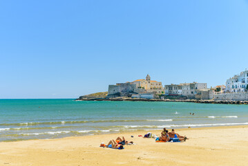 Vieste, Italy. View of the town with the beach of the Lungomare Cristoforo Colombo with some people. In the distance the Church of San Francesco. September 5, 2022.