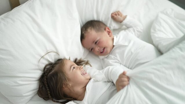 Adorable girl and boy smiling confident covering with blanket at bedroom