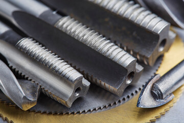 set of different drill bits,thread tap and mill cutters with caliper ruler on steel plate...