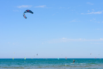 Vieste, Italy. In the sea of Scialmarino beach, a young man kitesurfing. In the background windsurfers and kitesurfers. September 7, 2022