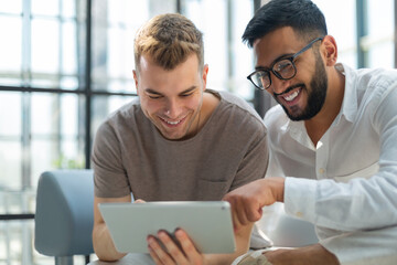 Happy business colleagues in modern office using tablet