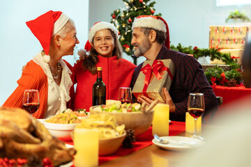 Happy family celebrating Christmas with Grandparents .Family make surprise for happy grandfather on Christmas , granddaughter gives xmas present .