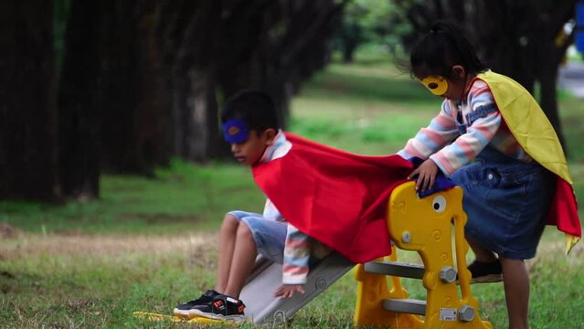 Children wearing masks and capes playing in the park.