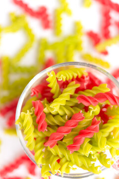 Close-up background of Fusille and Rotini in a glass bowl on white. pasta colorata	