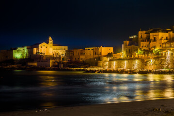 Vieste, Italy. Night view of the historic center of Marina Piccola. In the distance the Church of...