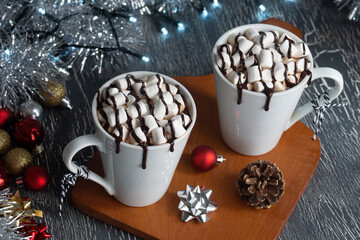 Hot Chocolate or Cocoa with Marshmallows Covered in Chocolate Sauce in Two Mugs with Festive Christmas Decorations