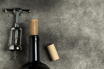 Portuguese wine. Bottle, corkscrew and cork on a black background.