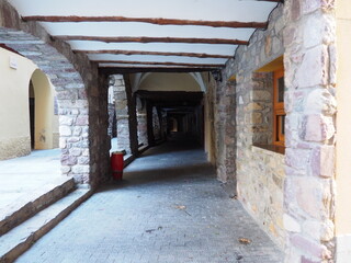 antiguo porche medieval con arcos de medio punto  separados por robustas conlumnas de piedra, techo de cal blanca y vigas de madera,  pont de suert, lerida, españa, europa
