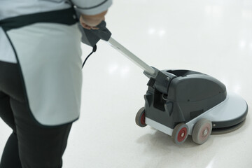 Fototapeta premium Woman maid cleaning floor with machine cleaner in the business office.Big cleaning day.Floor care with machine in hospital.