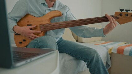 man enjoy hobby playing on guitar watching online tutorial on laptop leisure time at home