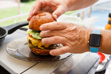 modern elderly man at home preparing a homemade hamburger on the grill
