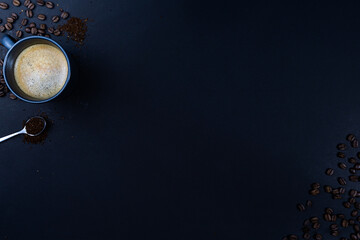 a cup of coffee and roasted coffee beans and grounded coffee on silver spoon on black background