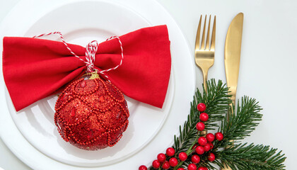 Christmas table setting, celebration dinner. Golden cutlery and red napkin on white, overhead