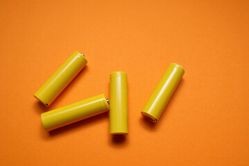 AA rechargeable batteries on orange with clipping path. Yellow batteries on a yellow pastel background