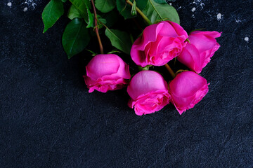 Fototapeta premium Pink roses, the bouquet is placed on a dark stone board. The scene depicts holiday greetings as well as love and romance.