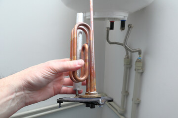 Repair and maintenance of boilers. Man's hand putting a new water heater in a boiler.