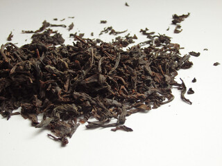 Black large-leaf tea as a background. Large dry black tea leaves isolated on white background