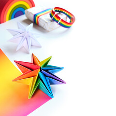 Vibrant neon rainbow origami paper stars. LGBTQ community rainbow flag colors. handmade DIY Christmas decor, copy-space. Origami Xmas stars and gifts in boxes. Handmade decor for LGBT.