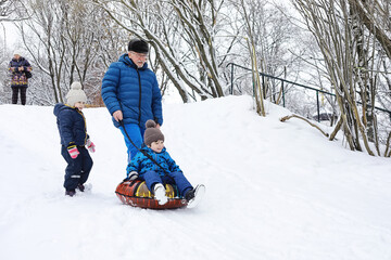 Children in the park in winter. Kids play with snow on the playground. They sculpt snowmen and slide down the hills.