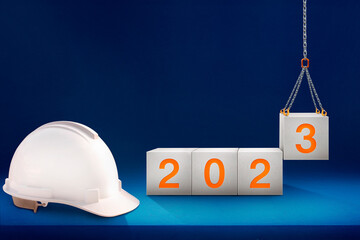 engineer working table and lifting concrete cubes by crane construction for preparation of welcome 2023, new year party, and change new business.