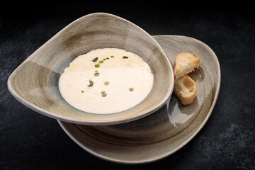 Mushroom cream soup with homemade bread, on dark concrete