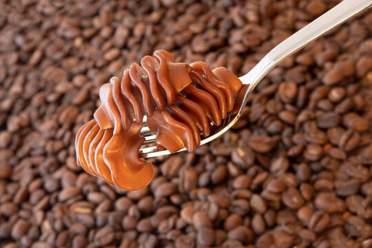 Close-up of coffee pasta on a fork against a background of coffee beans
