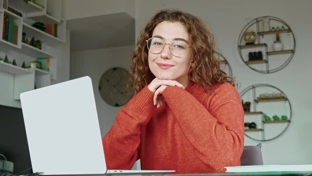 Young smiling happy pretty business woman student sitting at table at home office with laptop computer looking at camera advertising elearning online, remote work, business webinar. Portrait.