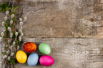 Spring Easter composition of spring branches and colored eggs on a wooden table, top view, copy space