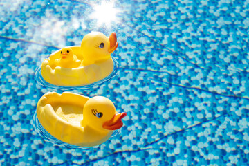 Yellow duck toys in the pool against the backdrop of beautiful blue water, family vacation concept