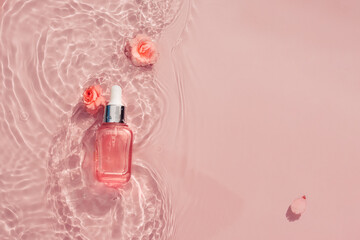 Pink bottle with rose oil, serum on water background with flowers and waves