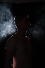 Fototapeta na wymiar silhouette of a guy. men in the dark. smoke . steam . man in a dark room.