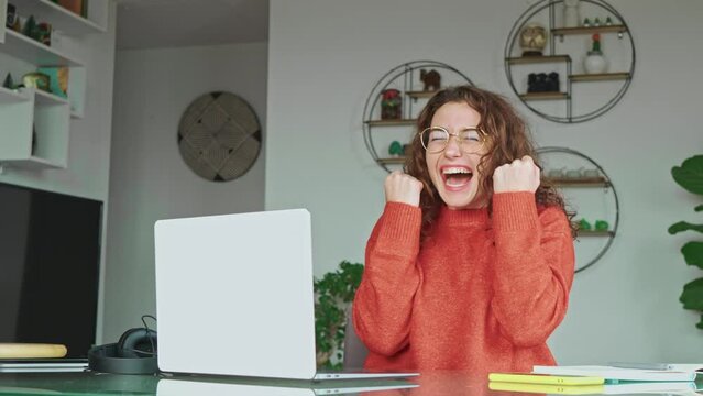 Happy girl student winner looking at laptop receiving good news in email celebrating achievement success. Excited woman winning online, getting new approved job opportunity using computer at home.