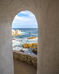 Passage d'un chemin de randonnée en bord de mer par une porte voutée