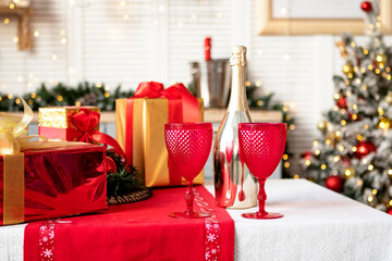 Red wine glasses and a bottle of champagne on the festive table at home. Christmas concept, New Year celebration