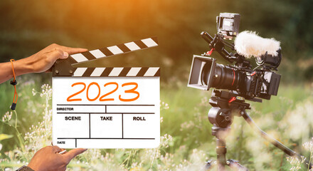 2023- handwritten on film clapperboard. film crew holding film clapperboard and a camera filming a...