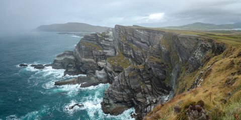 Kerry cliffs with green grass and dramatic clouds in cloudy autumn day, Kerry, Ireland.