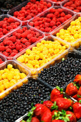 Colourful mix of different fresh berries at market. Raspberries, strawberries and bilberries.