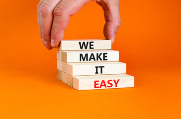 We make it easy symbol. Concept words We make it easy on wooden cubes. Beautiful orange table orange background. Businessman hand. Business motivational we make it easy concept. Copy space.