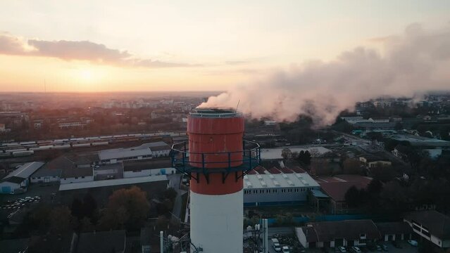 Aerial drone footage of an Industrial Chimney, smoke emission, flying near the pollutant in the air, burning gas for heat
