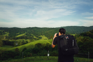 Young man traveller with backpack using camera take a photo of nature