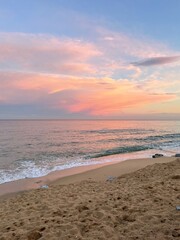 Puesta de sol desde la orilla de la playa. Cielo con tonalidades rosadas y anaranjadas.