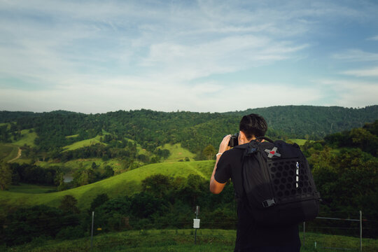 Young man traveller with backpack using camera take a photo of nature