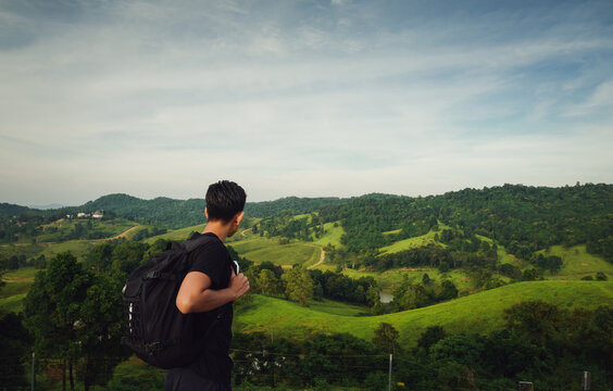rear view of young man traveller with backpack  look at faraway of mountain view and tuscany
