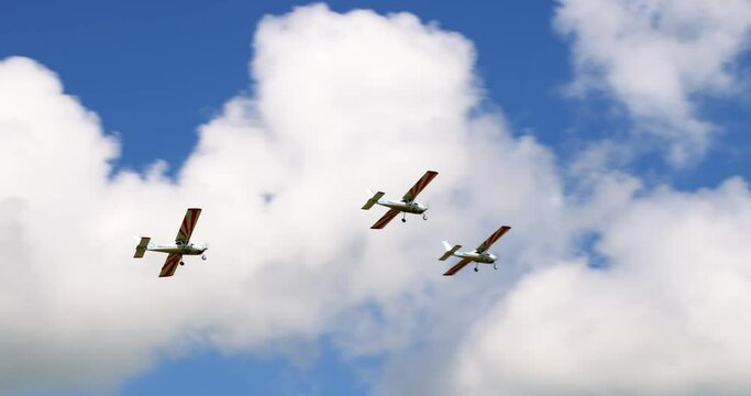 Classic light propeller planes flying in a sunny blue sky with white clouds