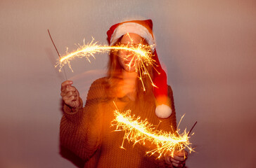 A woman in a New Year's hat with sparklers.