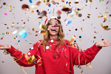 Woman in a New Year's hat is happy with confetti.