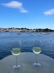 Copas de vino blanco con vistas espectaculares a la costa y al puerto pesquero de Cadaqués en la Costa Brava. 