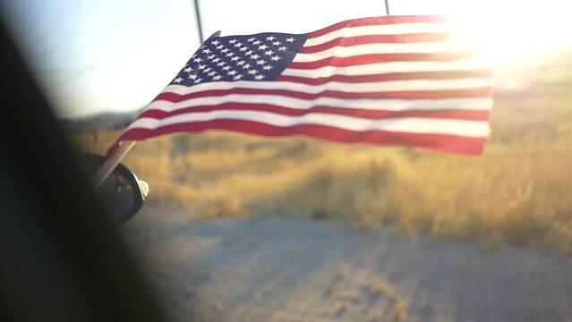Closeup of the Flag of the US waving in the wind from a car