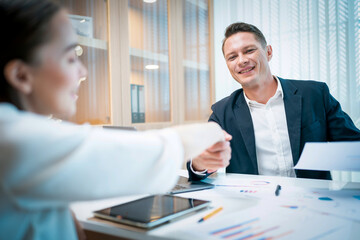 Caucasian businessman checking hands with young attractive businesswoman after finished business deals in office. Business and success concept