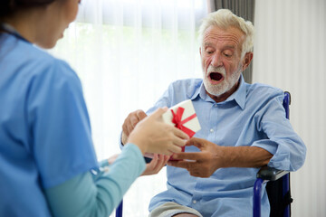 Obraz premium senior man taking a gift box from caregiver for happy birthday